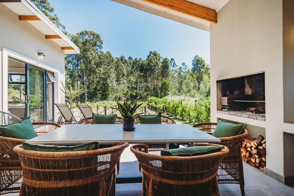 Covered outdoor deck with dining table, woven chairs, forest views