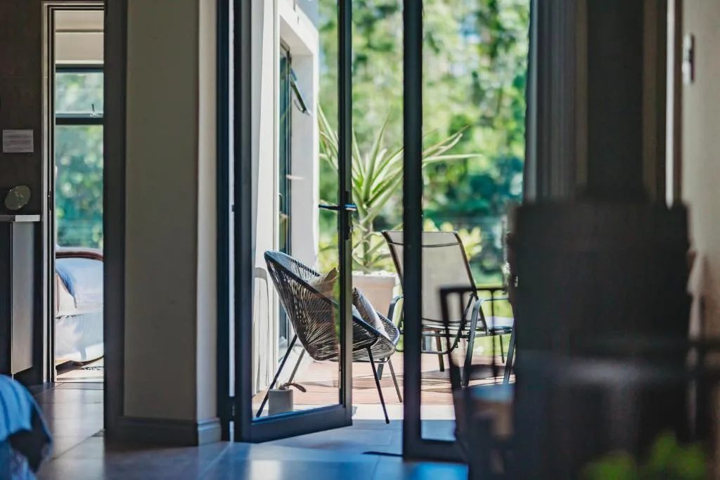 Modern patio with black chairs and potted plant overlooking lush garden