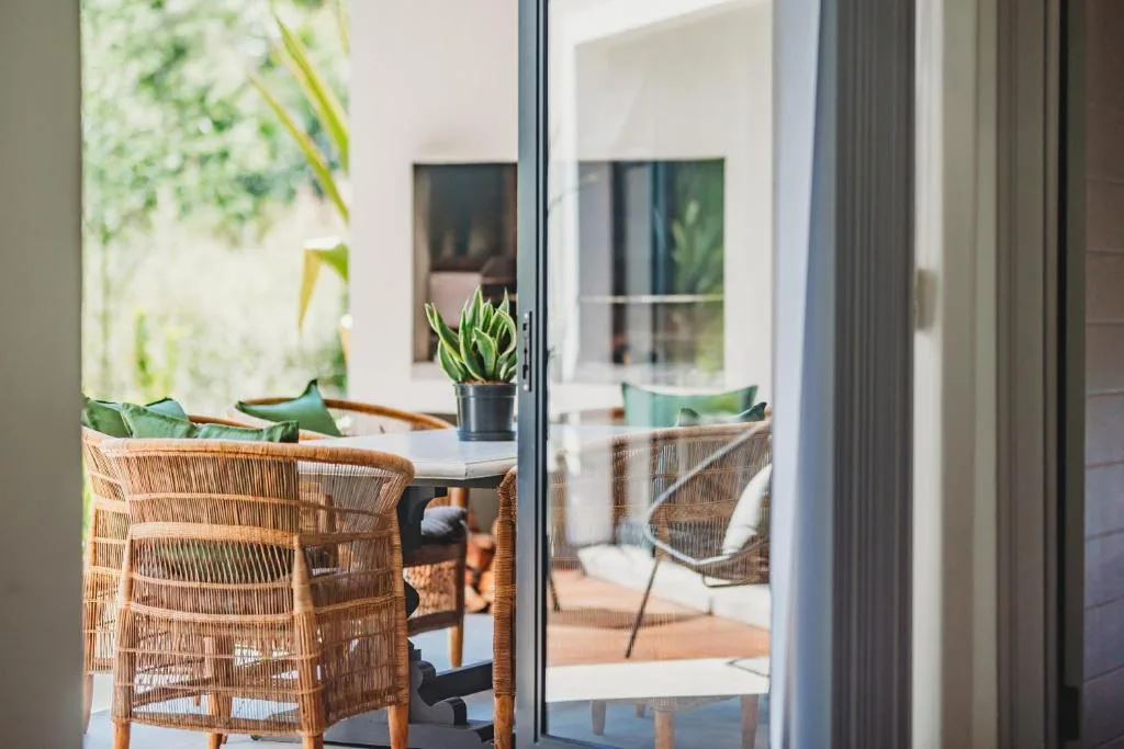 Woven rattan chairs with green cushions on sunny outdoor patio