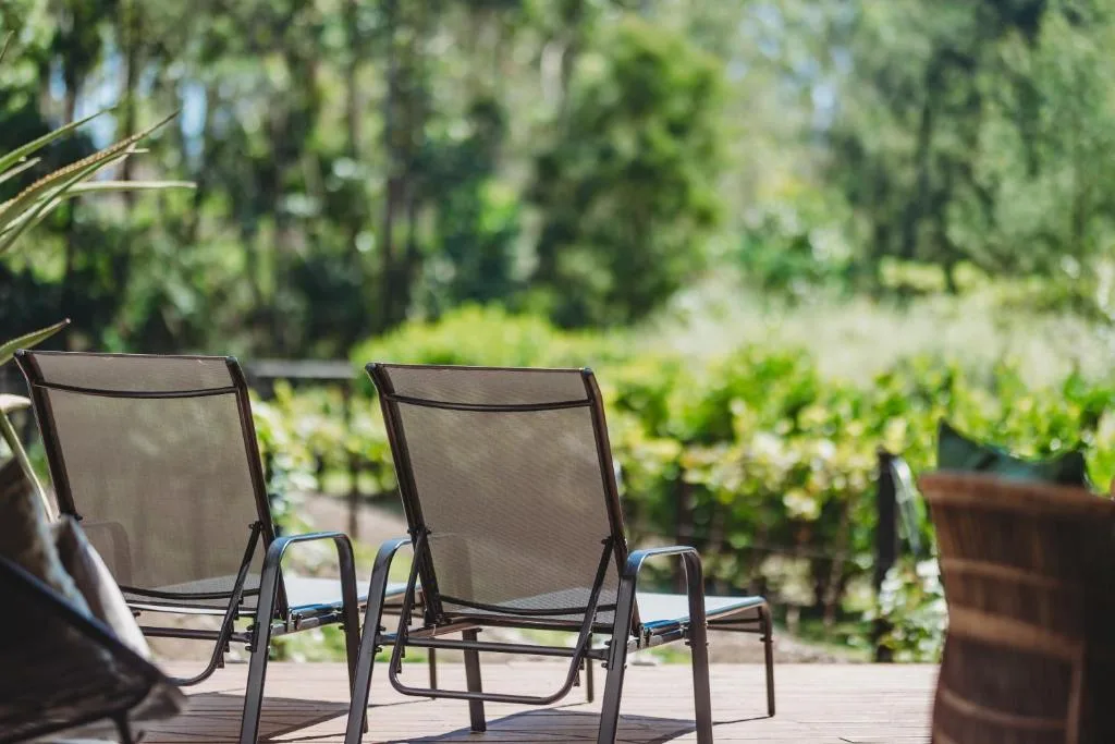 Lounge chairs on wooden deck overlooking lush green garden