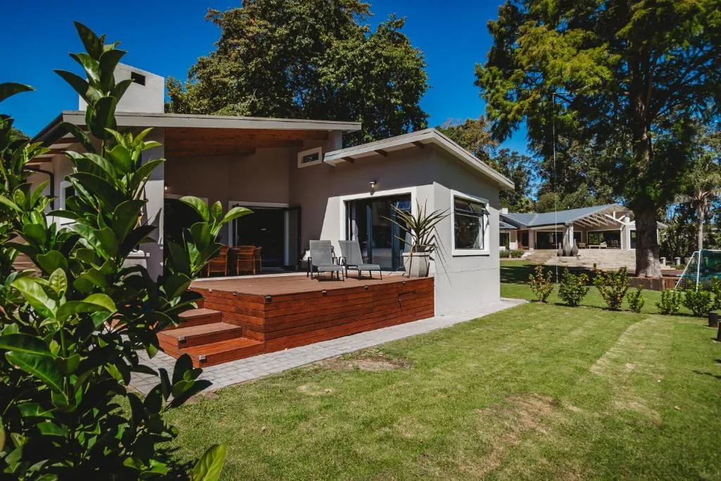 Modern white cottage with wooden deck and manicured garden lawn