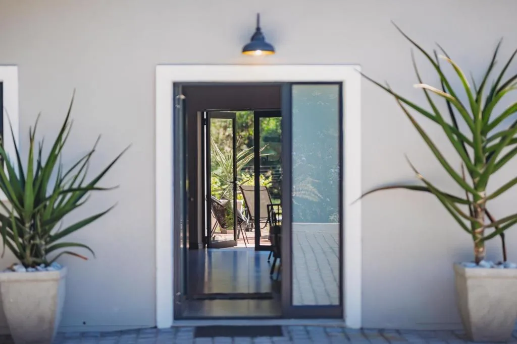 Modern entrance with dark-framed sliding doors and potted plants flanking entry