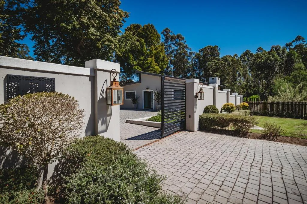 Modern white property entrance with paved driveway and manicured garden landscaping