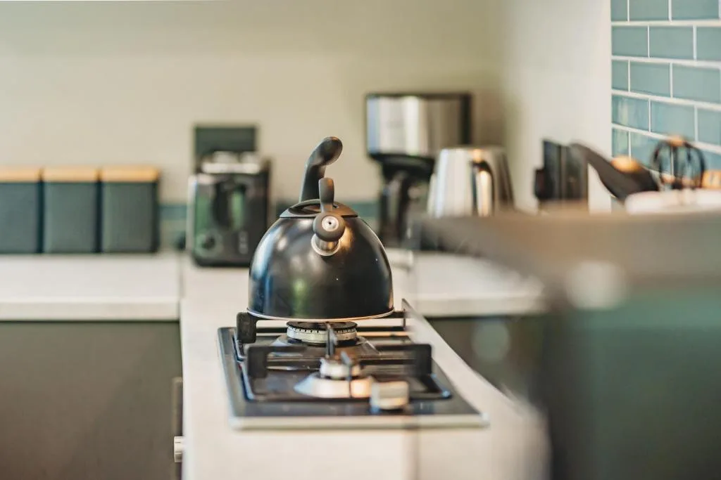 Modern kitchen with gas stove, kettle, and teal tile backsplash