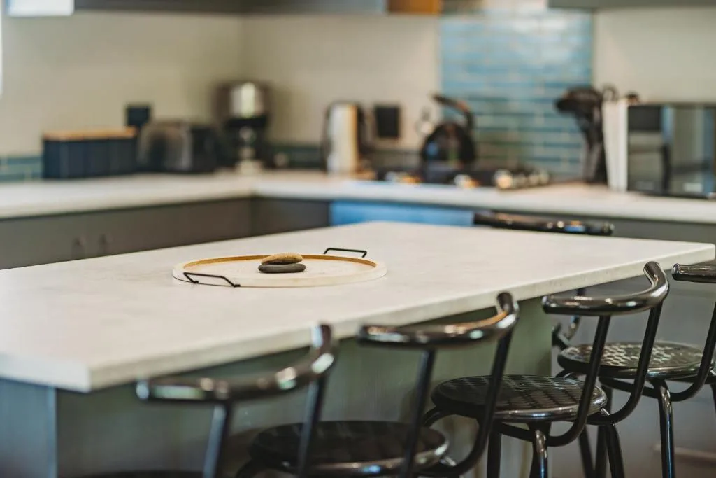Modern kitchen with white countertop, black chairs, and appliances