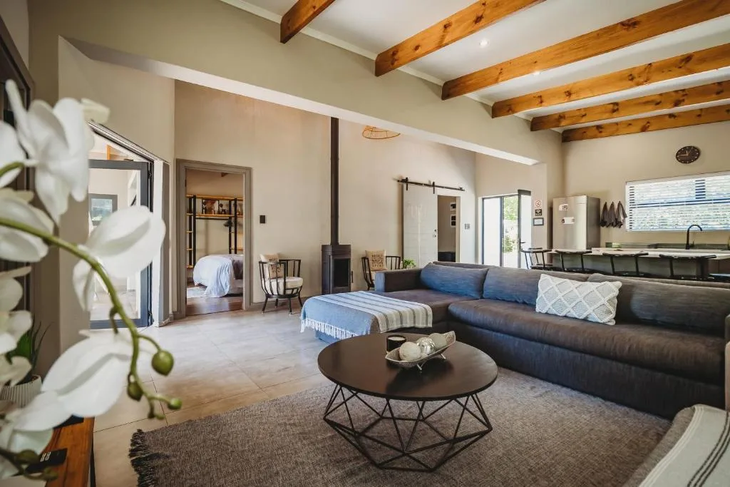 Open-plan lounge with dark sofa, round coffee table, and exposed wooden beams