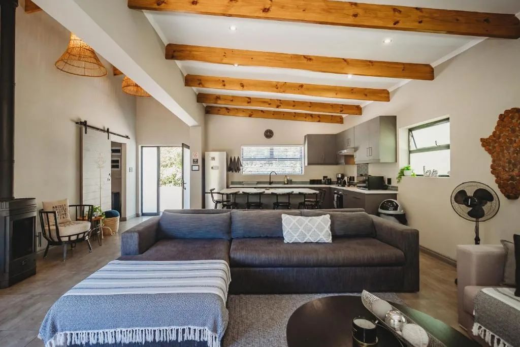 Modern lounge with dark sofa, blue accents, and exposed wooden beams