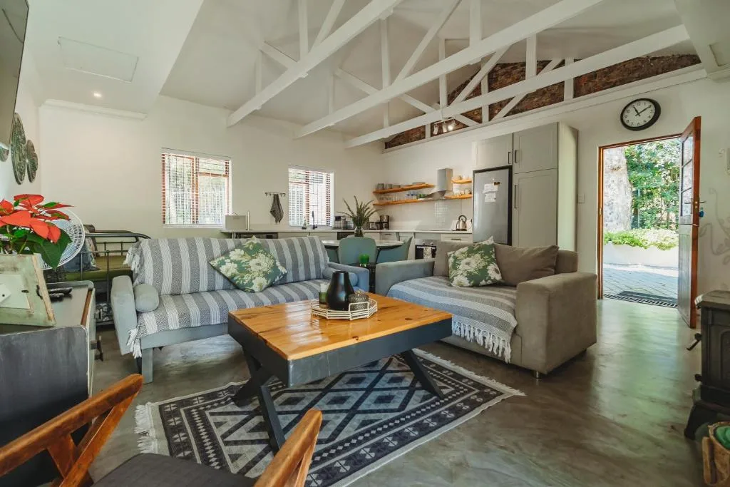 Open-plan lounge with striped sofa, wooden coffee table, and kitchen visible