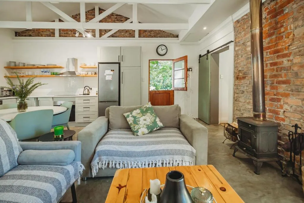 Open-plan lounge with sofa, armchair, and exposed brick fireplace wall