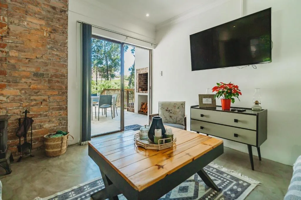 Modern living room with wooden coffee table, wall-mounted TV, and deck access