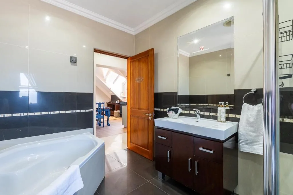 Modern bathroom with white vanity sink, dark cabinetry, and soaking tub