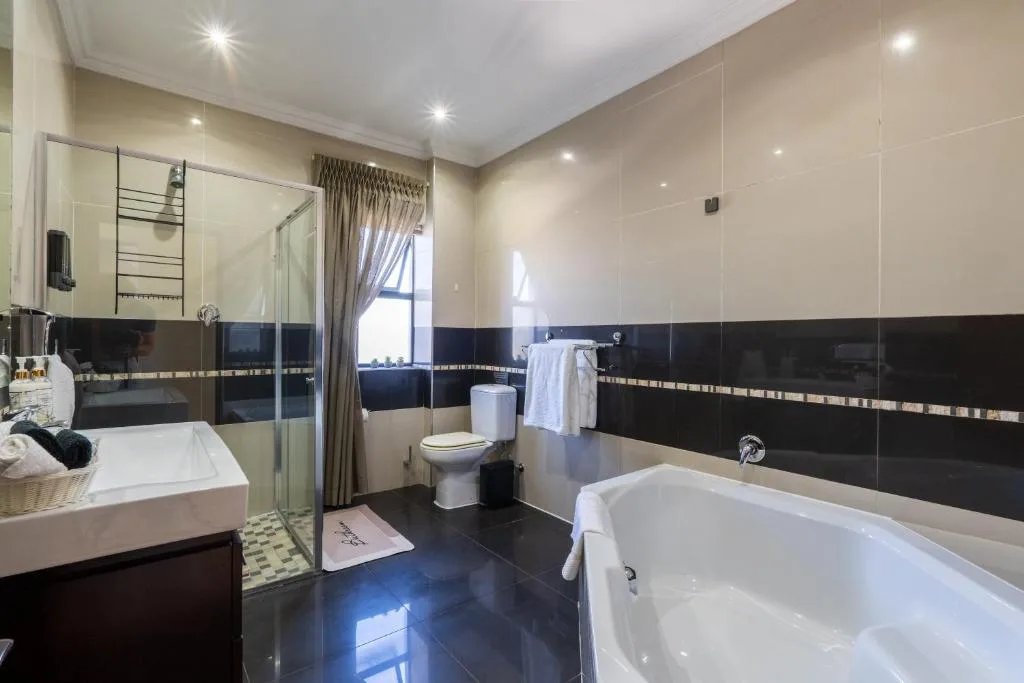 Modern bathroom with dual vanity, walk-in shower, freestanding tub, and black tile accents