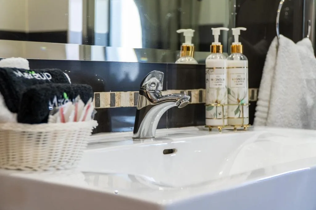 Modern bathroom vanity with chrome faucet, toiletries, and white towels