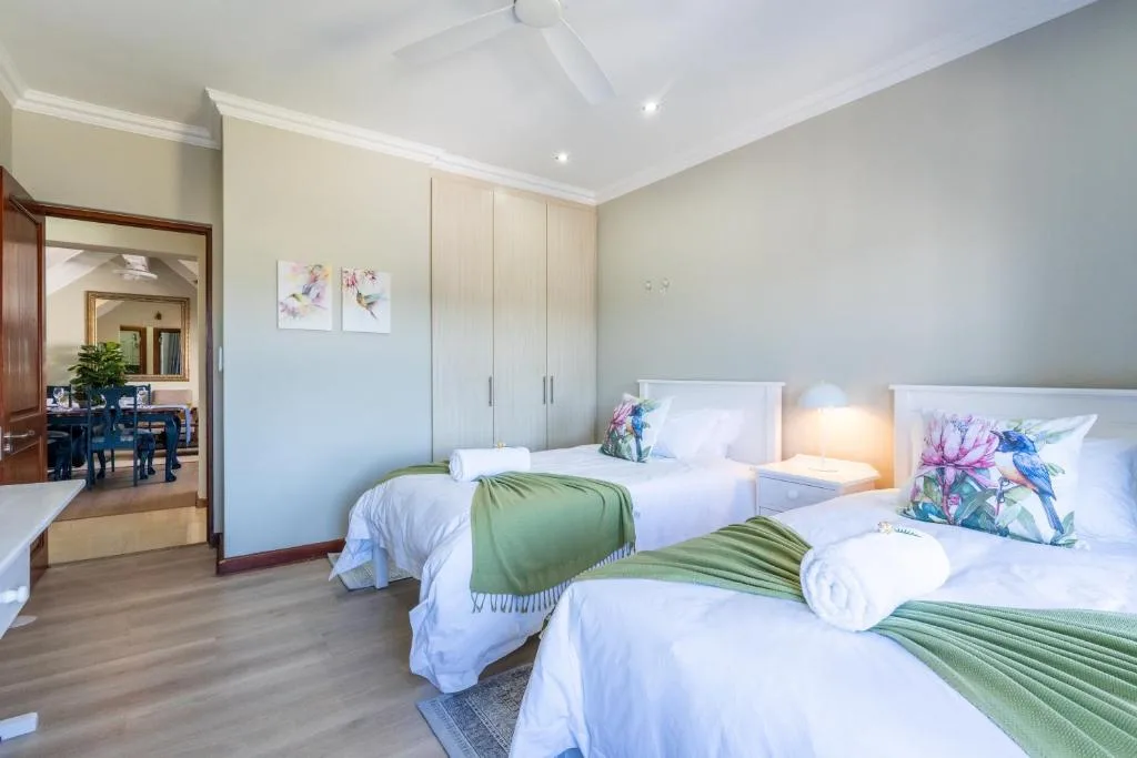 Spacious bedroom with two twin beds, green accents, modern lighting