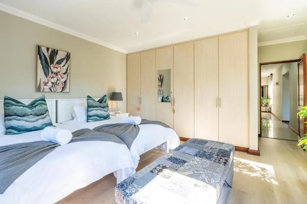 Spacious bedroom with twin beds, teal cushions, and wooden wardrobe