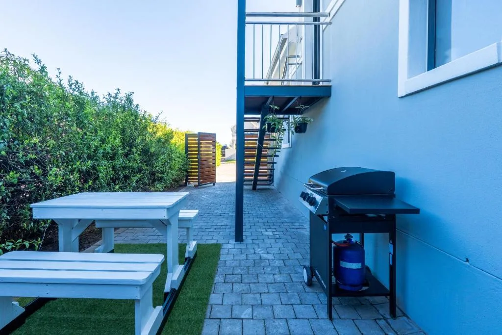 Modern patio area with white benches, braai grill, and manicured landscaping