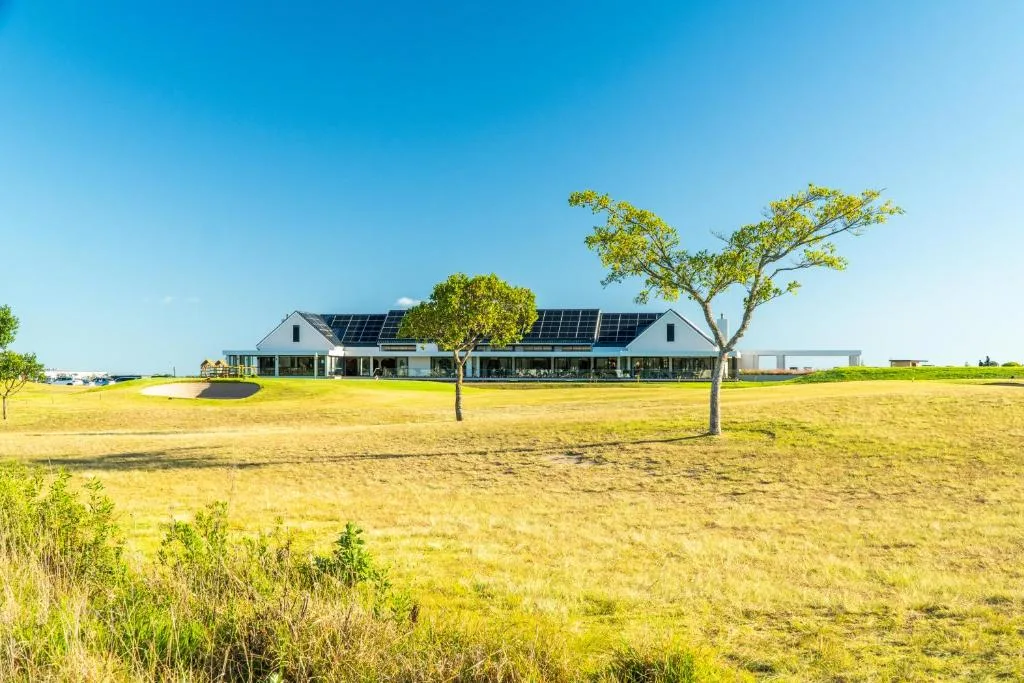 Modern white farmhouse with solar panels set in expansive green countryside