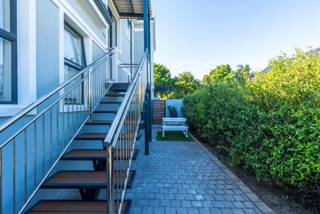 Modern white building exterior with metal staircase and manicured garden pathway