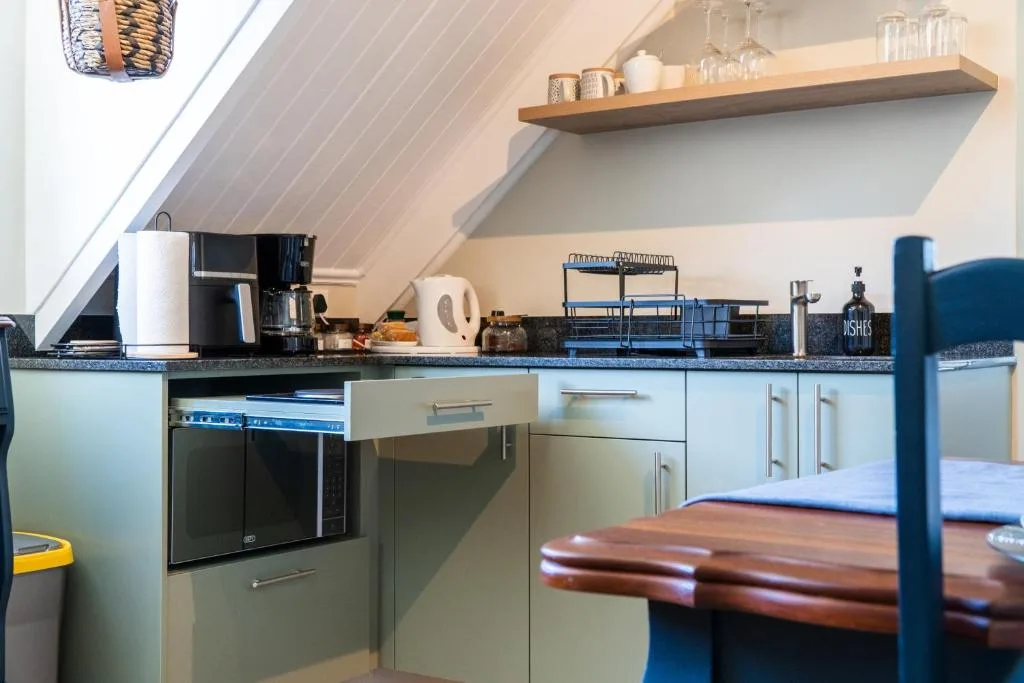 Modern kitchen with pale cabinets, black countertop, and stainless steel appliances