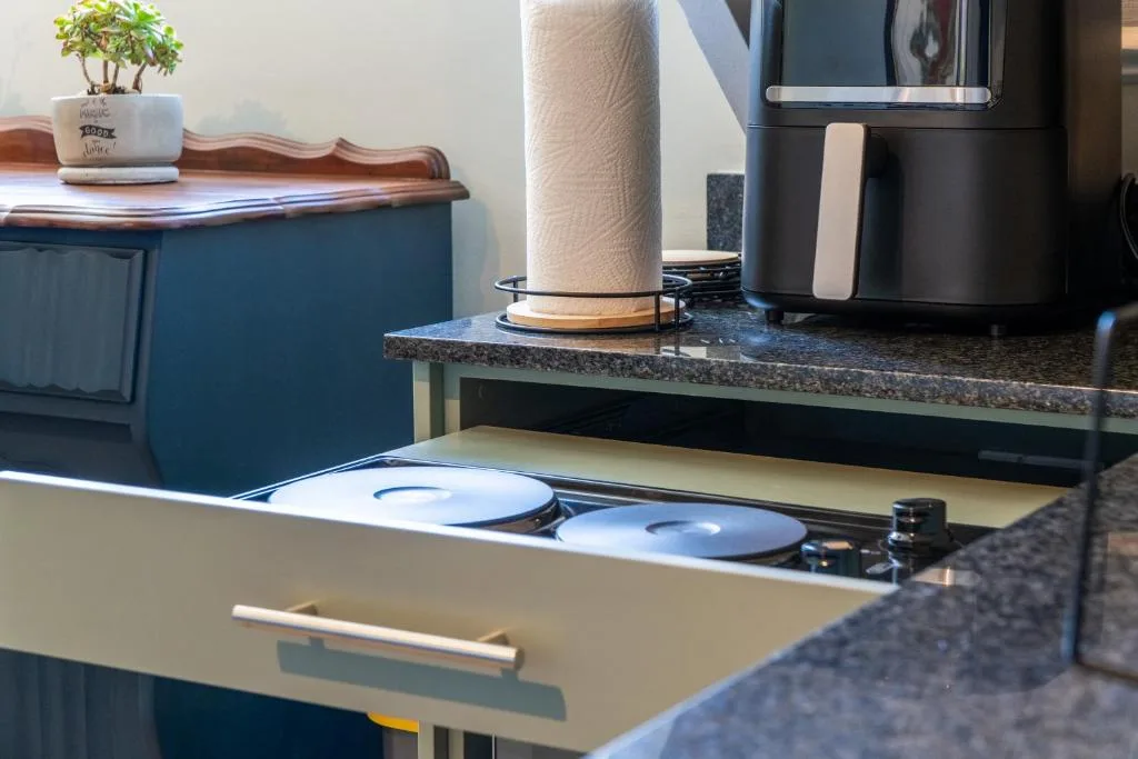 Modern kitchen with granite countertop, stove, black appliances, potted plant