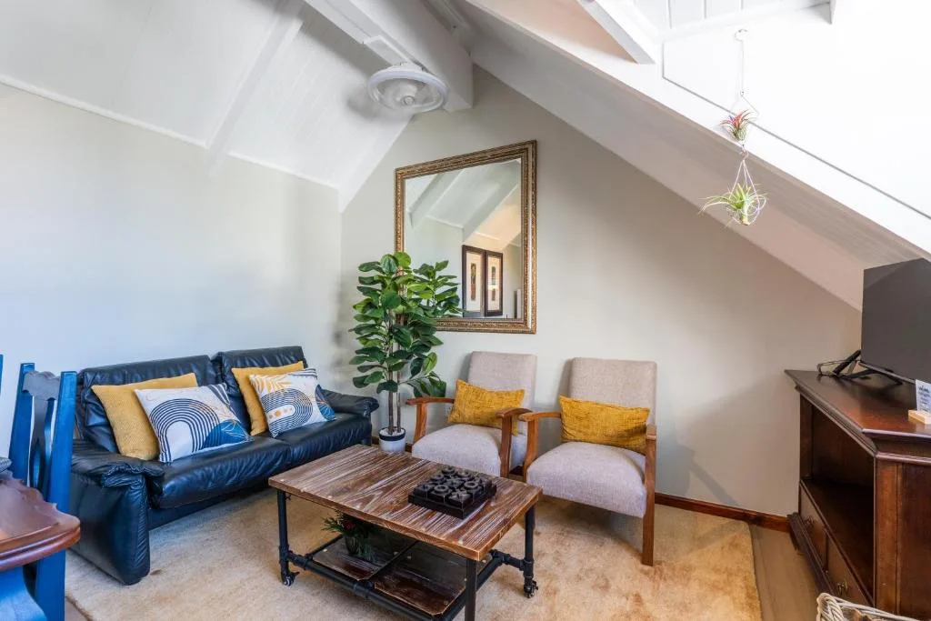 Bright attic lounge with blue leather sofa, wooden coffee table, and yellow accents