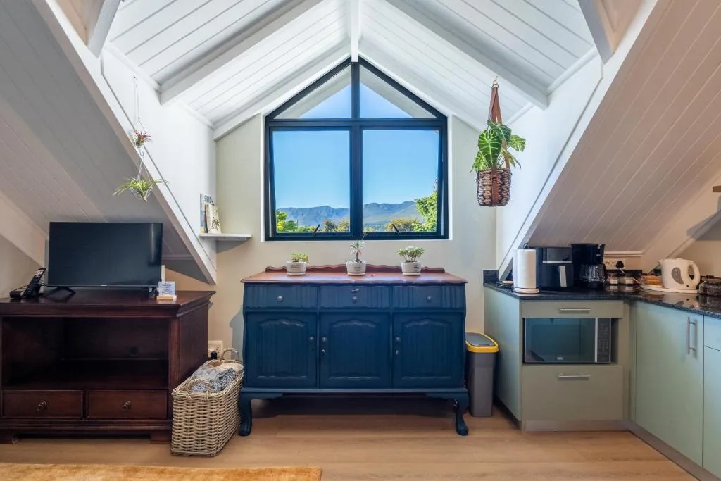 Modern loft lounge with TV, blue cabinet, and mountain views through skylights