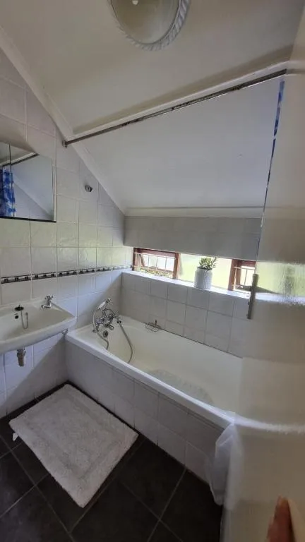 Bright bathroom with white tiles, bathtub, sink, and window light