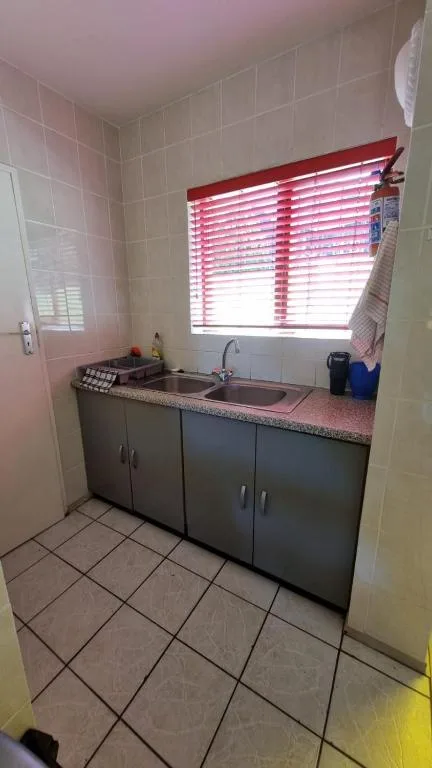 Compact bathroom vanity with dark cabinetry and pink striped window blinds