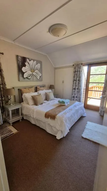 Bright bedroom with queen bed, neutral bedding, and glass doors opening to deck
