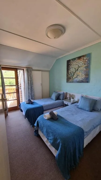Bright bedroom with two twin beds, blue bedding, and turquoise accent wall