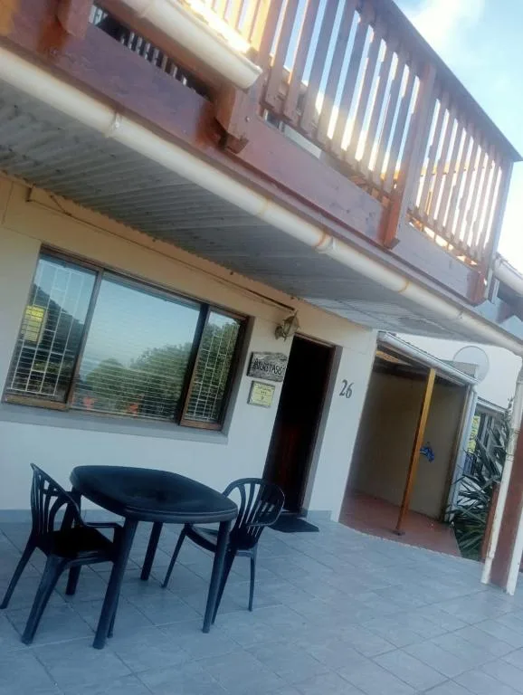 Patio area with round table and black chairs beneath wooden deck railing