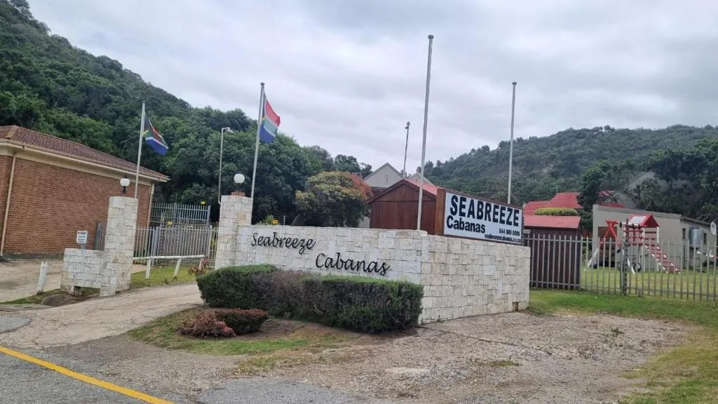 Seabreeze Cabanas entrance with signage, flags, and tree-lined surroundings