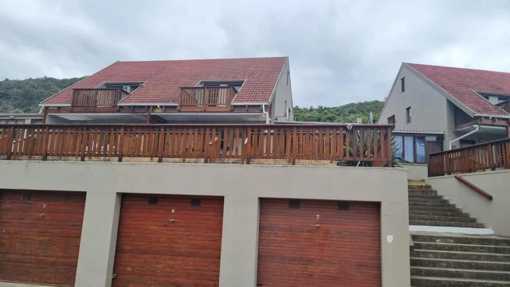 Modern multi-level residential building with red tile roof and wooden deck railings