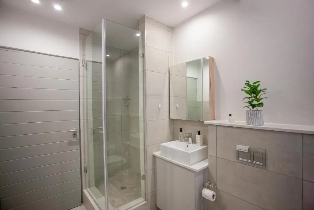 Modern bathroom with glass shower enclosure, white vanity sink, and mirror