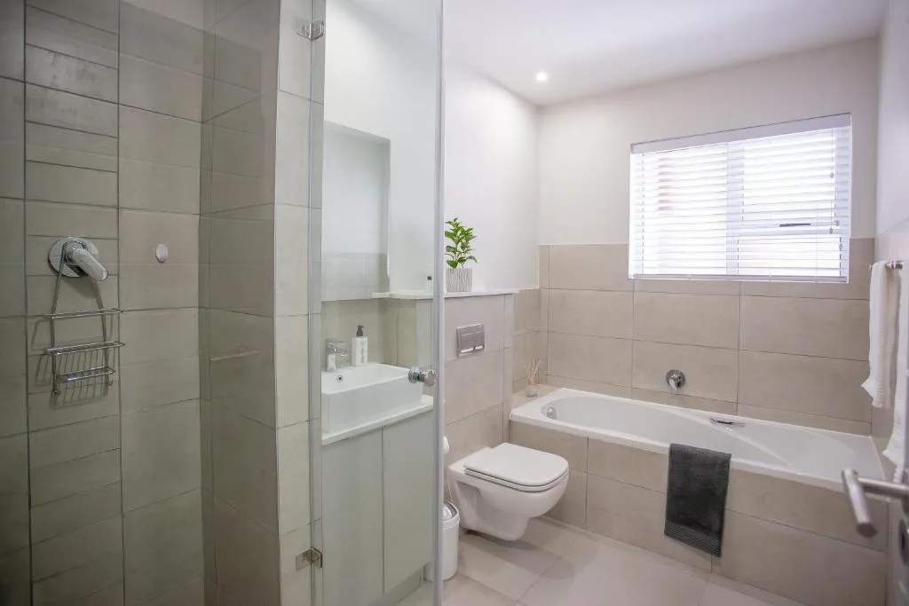 Modern bathroom with walk-in shower, bathtub, toilet, and vanity sink