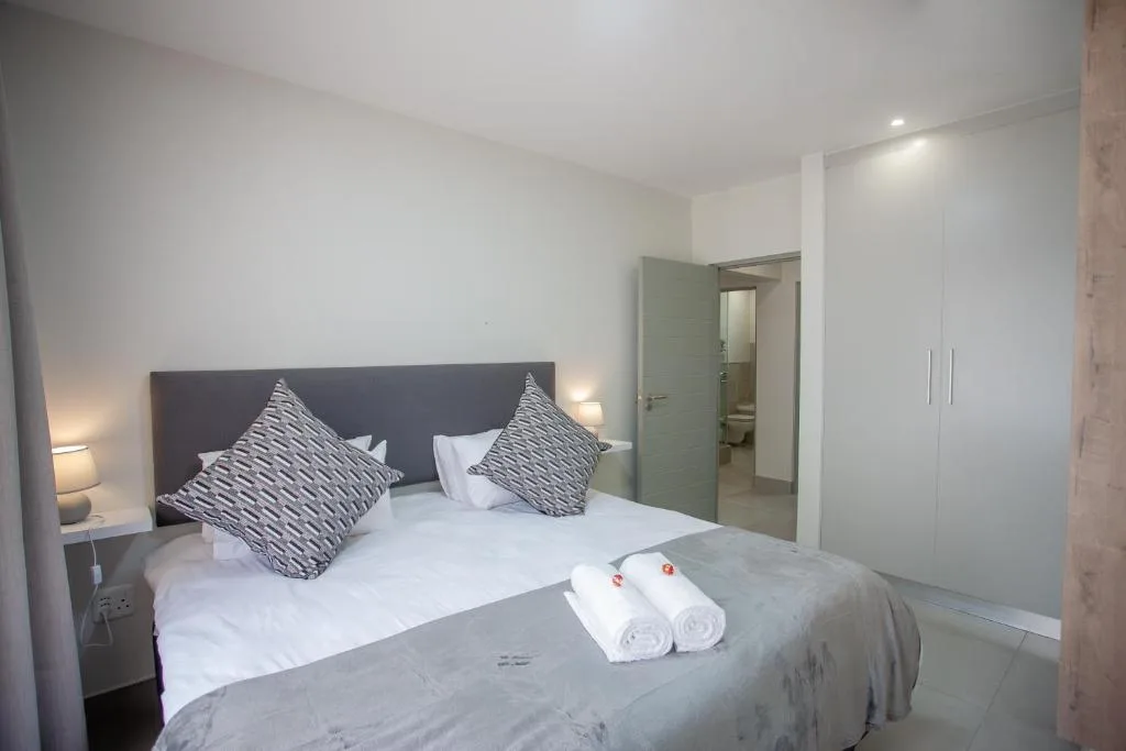 Modern bedroom with queen bed, patterned pillows, and en-suite bathroom access