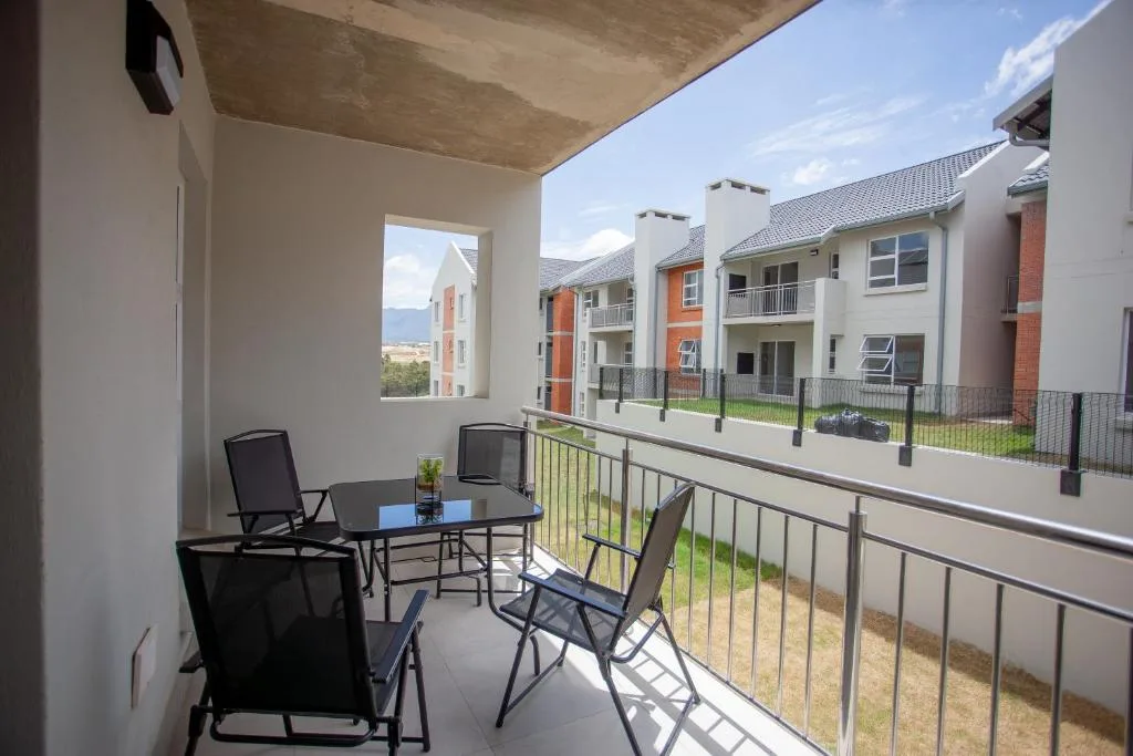 Covered balcony with black outdoor chairs and table overlooking residential complex