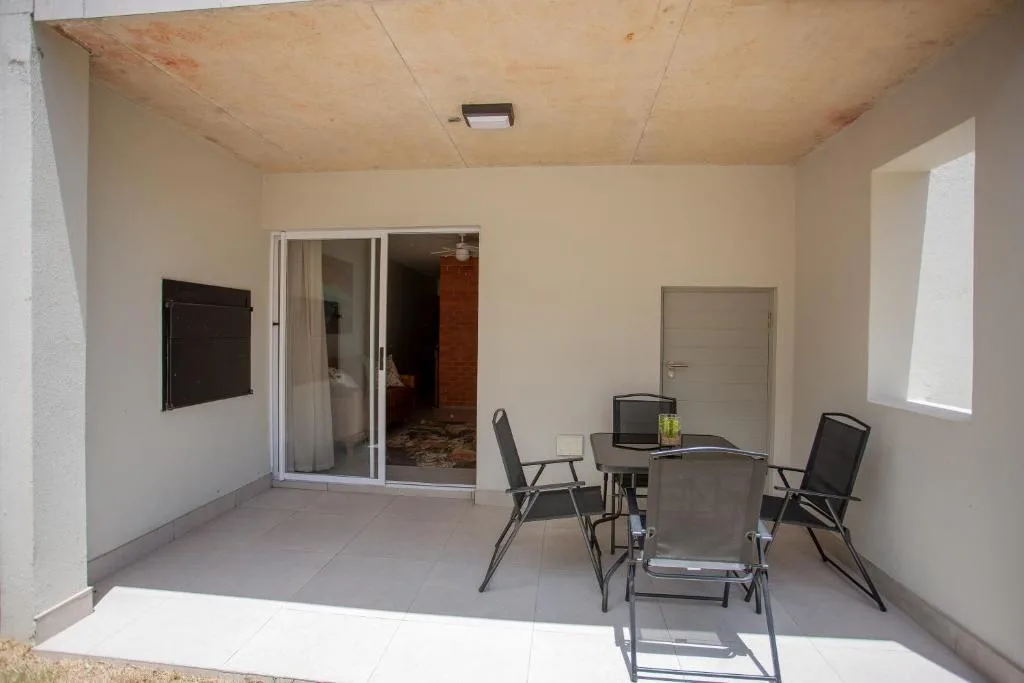 Covered patio with dining table and chairs, sliding glass doors to interior