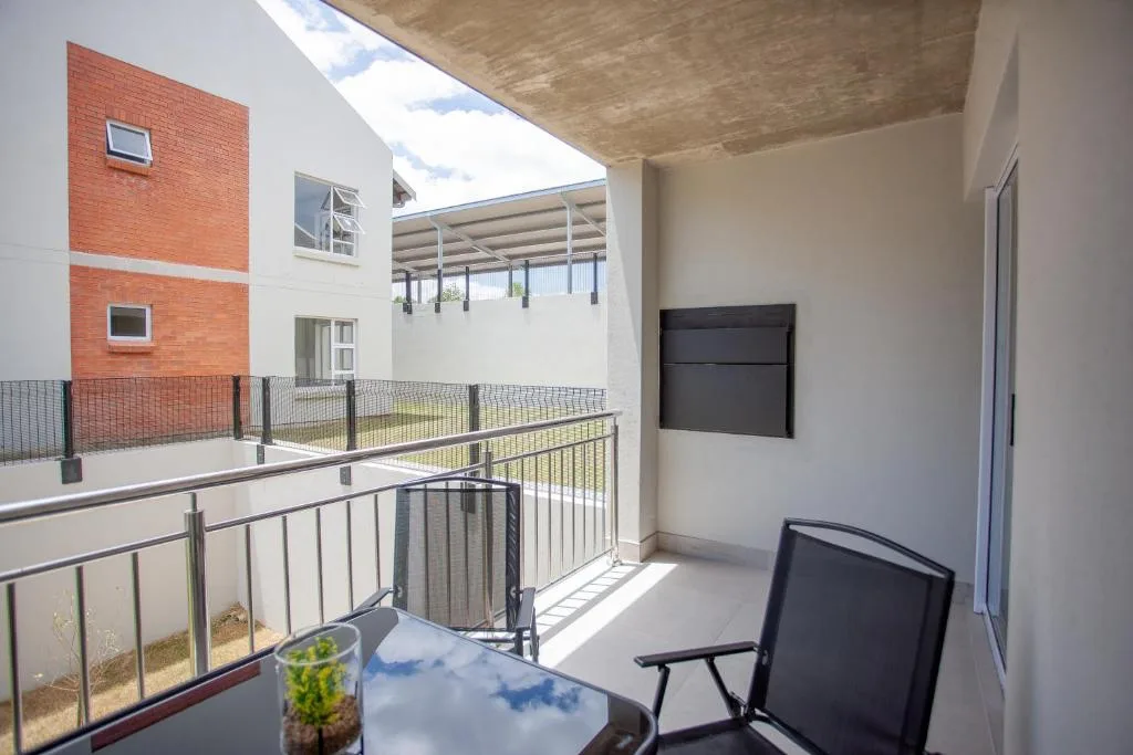 Modern balcony with metal railings overlooking courtyard and brick building facade