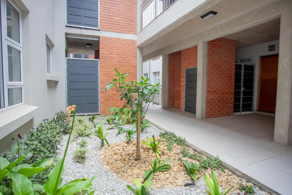 Modern apartment courtyard with brick walls, planted garden, and covered entrance