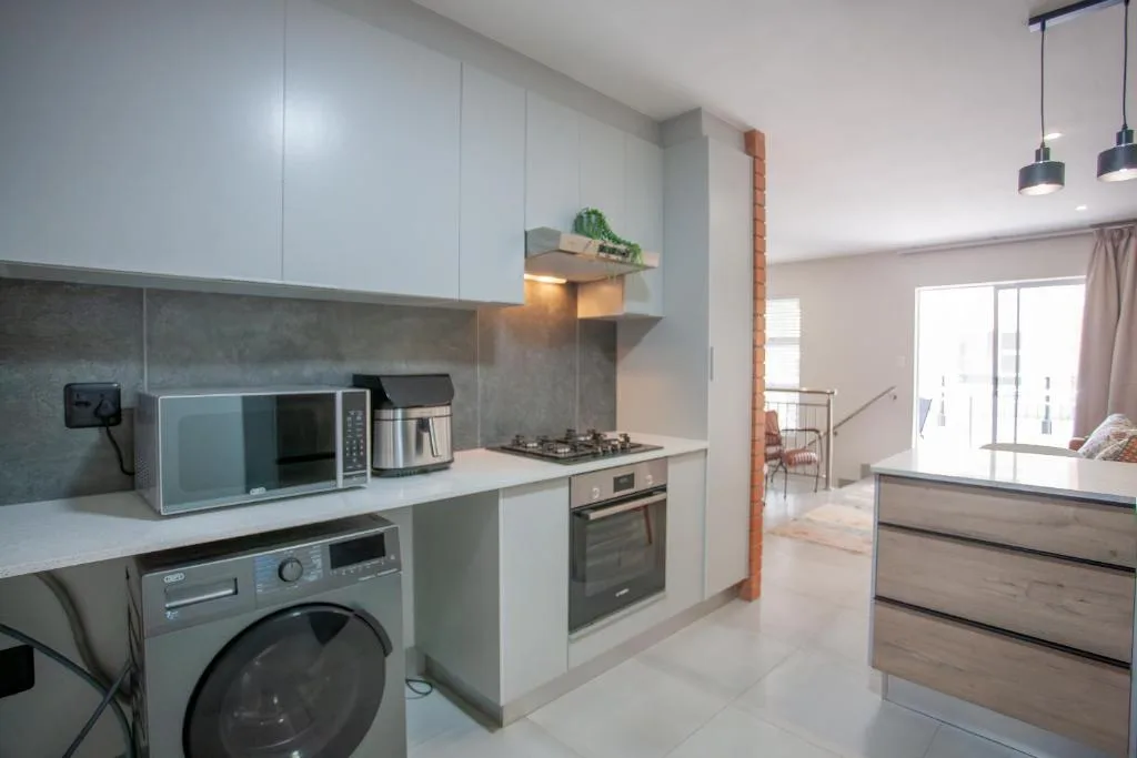 Modern kitchen with white cabinetry, stainless steel appliances, and gray backsplash