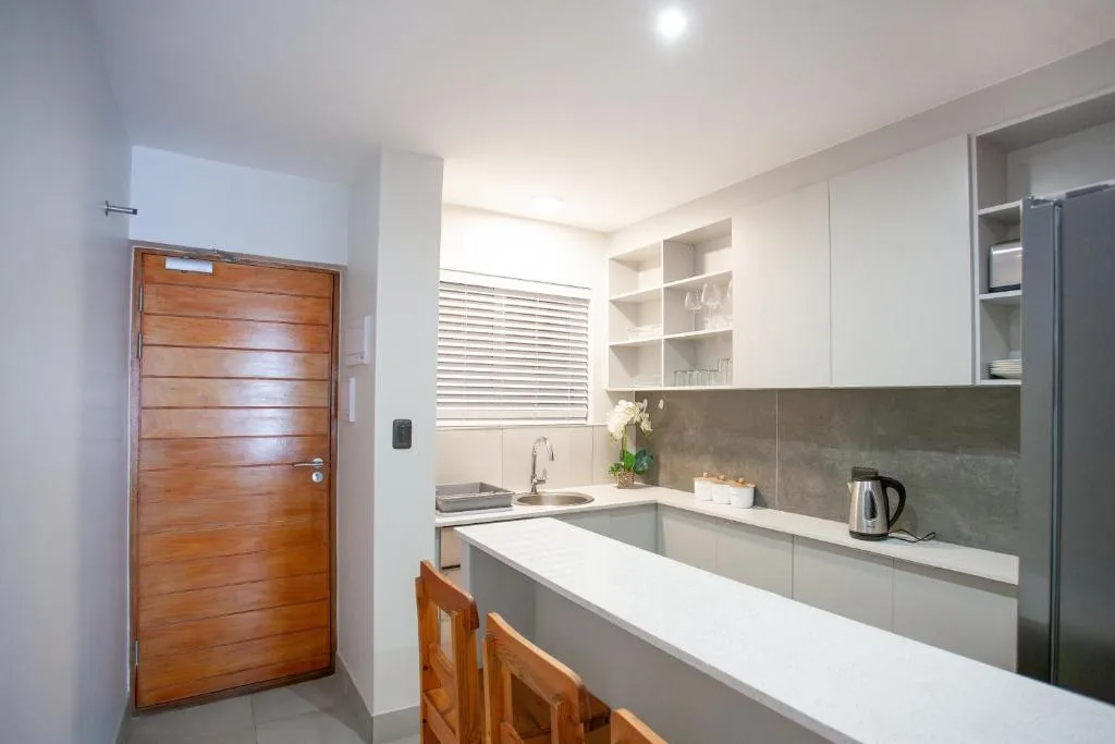 Modern kitchen with white counters, grey backsplash, and stainless steel appliances