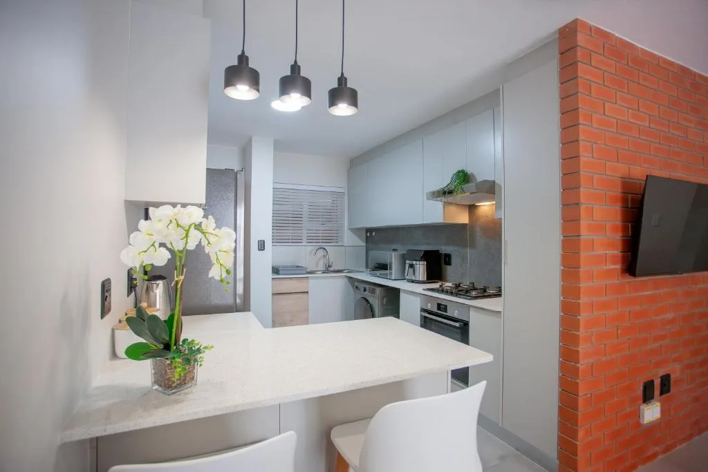 Modern kitchen with white cabinetry, stainless steel appliances, and pendant lighting