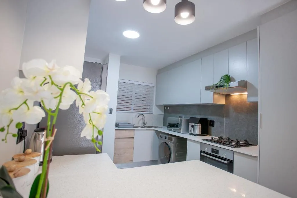 Modern kitchen with white cabinetry, stainless steel appliances, and orchid flowers