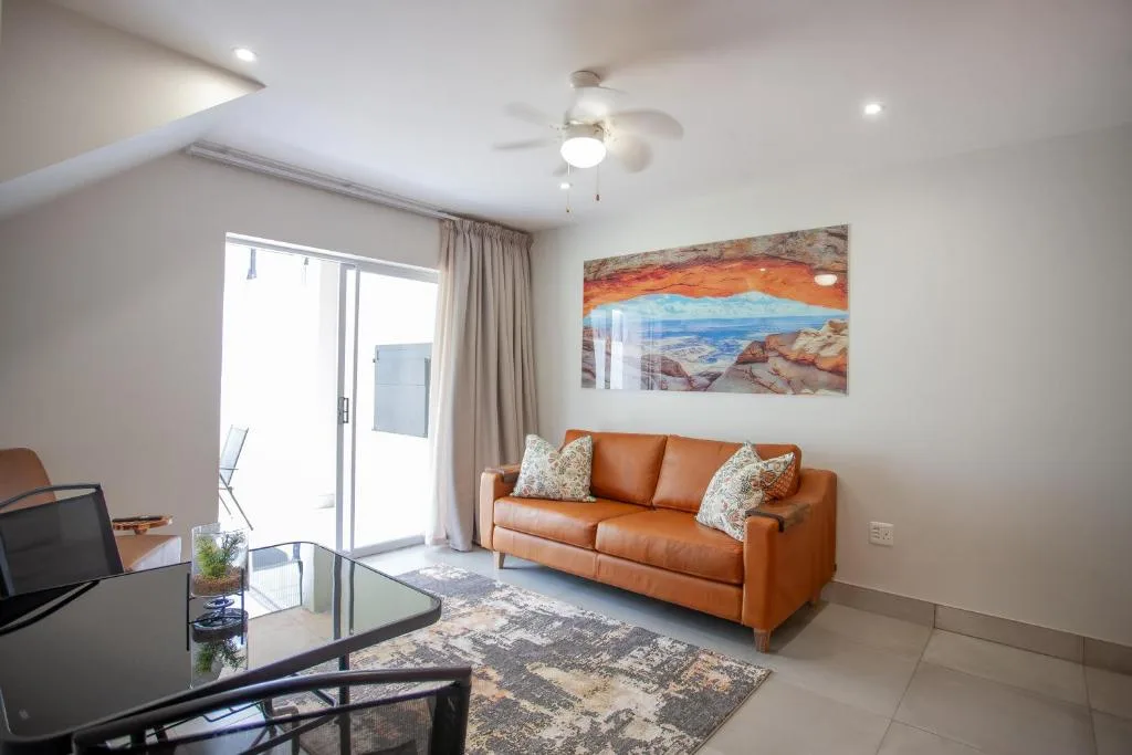 Modern lounge with orange leather sofa and scenic landscape artwork on wall