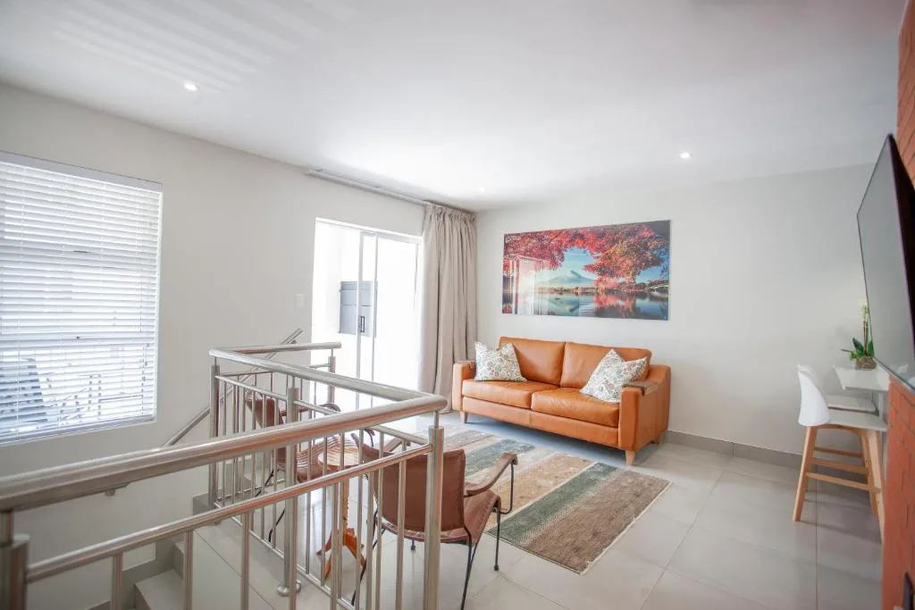 Open-plan lounge with orange sofa, stairs, and modern furnishings