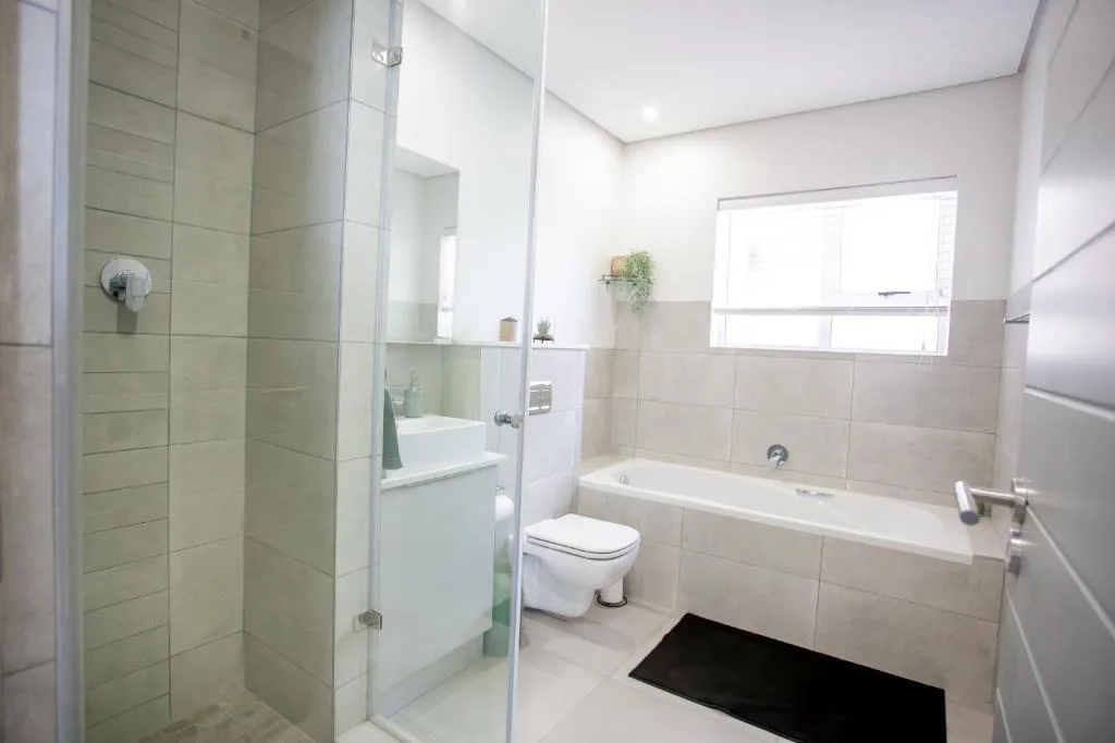 Modern bathroom with shower, bathtub, toilet, and vanity mirror