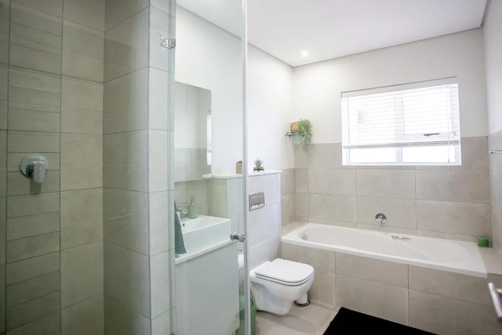 Modern bathroom with walk-in shower, bathtub, toilet, and vanity sink