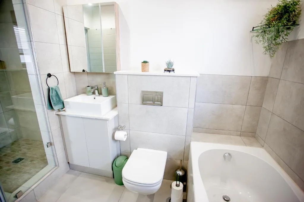 Modern bathroom with white vanity, toilet, bathtub and walk-in shower