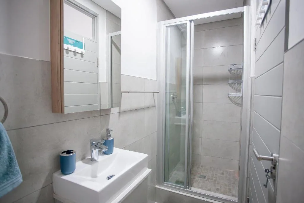 Modern bathroom with white sink, mirror, and enclosed shower enclosure